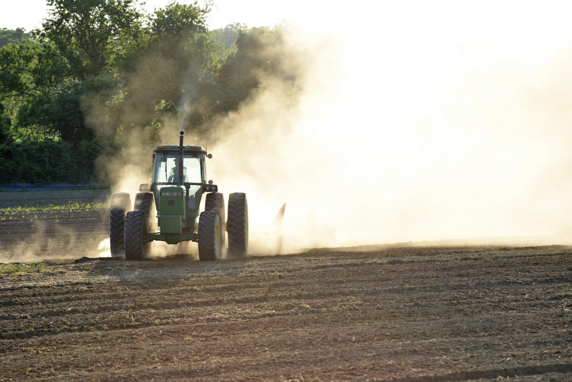 large green tractor at work in the fields